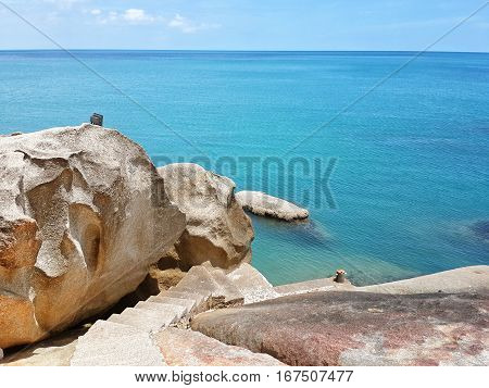 Rocks and blue sea. Staircase with stone steps down between the rocks to the sea