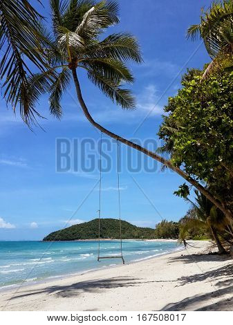 The sandy shores of the azure sea. Waves and palm tree with swing. Koh Samui Thailand