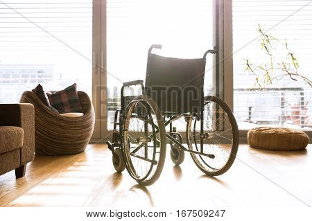 Empty wheelchair in sunny living room next to the couch