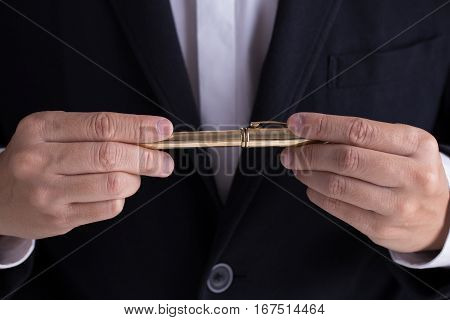 A man in black casual suit giving a gold fountain pen for sign the contract in formal way