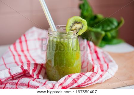 Homemade Healthy Green Smoothie With Spinach And Kiwi In A Jar Mug With A Straws On A Checkered Napk