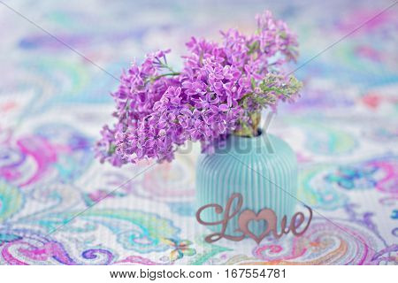 Bouquet of lilacs flowers in a vase on the table.