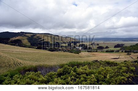 Broad panorama of the countryside in Victoria with green field in foreground. Grassy hills near Glenaire in Australia. Rural landscape near the forest in mountains. Hillside landscape.
