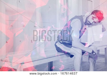 Tired man wiping sweat with towel in locker room