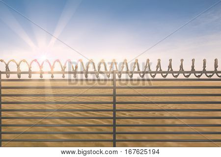Digitallly generated image of barbed wire on fence against desert scene
