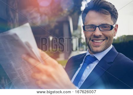 Portrait of handsome businessman reading newspaper outside office