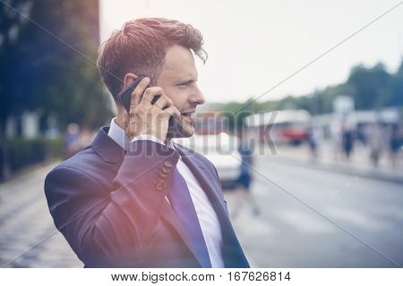 Handsome businessman speaking on mobile phone at street