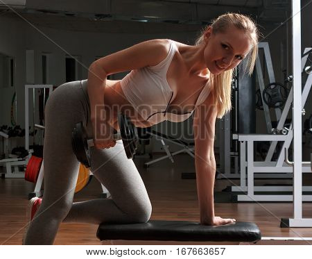 Girl trains with dumbbells in the gym