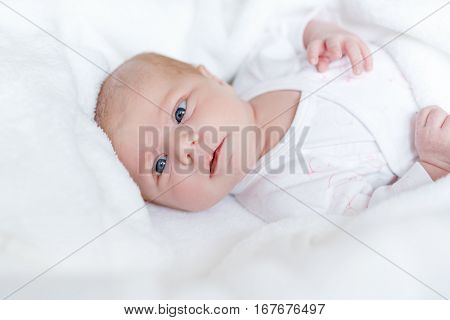 Cute adorable newborn baby in white bed and wrapped in blanket. New born child, little girl looking surprised at the camera. Family, new life, childhood, beginning concept.