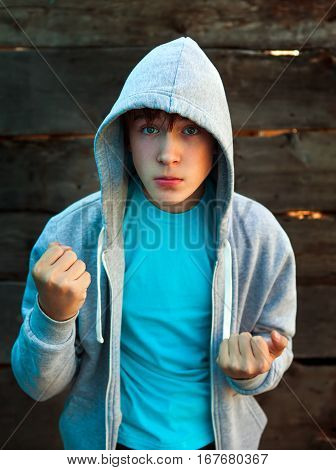 Angry Teenager in Boxer Pose on the Wooden Background