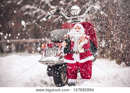Santa Claus toy standing near a red scooter in the snowy weather