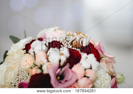 Pink wedding bouquet with cotton flowers and gold rings