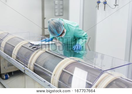 medical worker is bending on machine in pharmaciutical factory