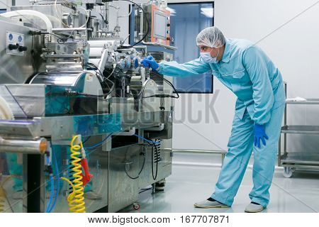 bended scientist works with manufacture machine in pharmaciutical factory