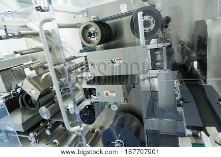 big machine with shafts and belts in pharmaciutical factory