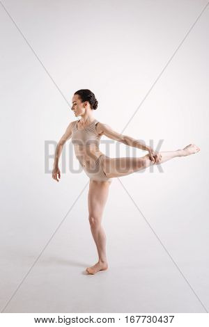Demonstrating a basic dance step. Flexible young proficient woman demonstrating her skills and making a step while dancing in the white colored studio