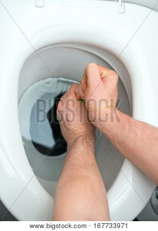 Plumber repairing toilet with a hand plunger.