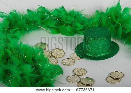 Green glitter hat with feather boa and gold coins for St. Patrick's Day background