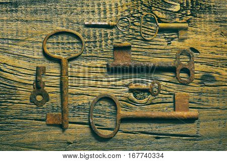 rusty medieval keys on worn out wood table. Antique and rusty medieval castle skeleton door keys with old corroded metal ring on antique weathered barn wood board planks
