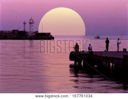 Sea and white beacon at the evening. Purple colors of sky and water.