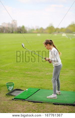Girl with cammock trains to play golf on green golf course at spring day