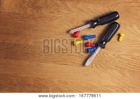 Kids toys tools: colorful screwdrivers, screws and nuts on wooden background. Top view. Flat lay.