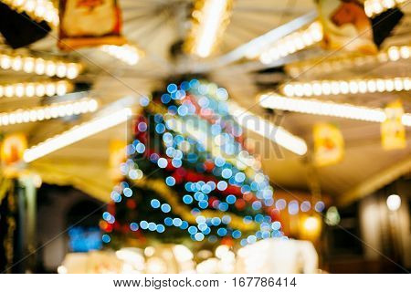 Defocused merry go round carousel detail with beautiful bokeh and silhouettes of visitors