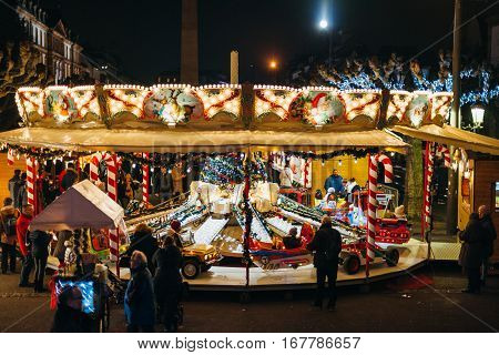 STRASBOURG FRANCE - DEC 20 2016: Elevated view of Merry-Go-Round with parents surveying their children at the funfair of the Christmas Market in Place Broglie in Strasbourg