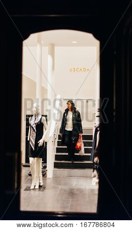 STRASBOURG FRANCE - DEC 20 2016: Woman descending stairs of an Escada store with shopping bags full with luxury clothes. Escada SE is a German luxury women's designer clothing company headquartered in Munich owned by Megha Mittal.