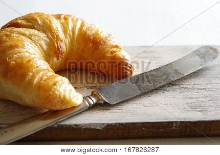 frest tasty croissant with old knife of a wooden board