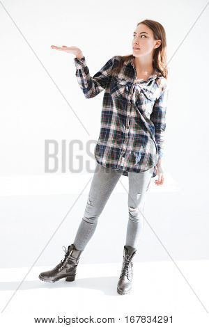 Full length of beautiful young woman standing and holding copyspace on palm over white background