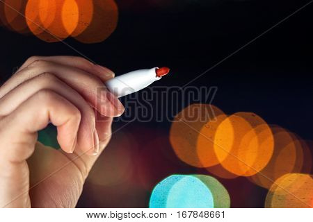 Female hand writing with red marker pen over transparent glass board as copy space bokeh light effect in background