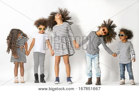 Five cute African girls in striped clothes holding hands on white background