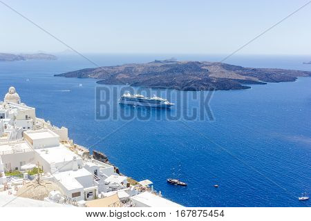 Beautiful panoramic view on the mediterranean sea, caldera and volcano. Traditional white architecture of Santorini island, Thira, Greece. Cruise ship in blue sea.