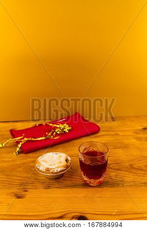 Shot glass with slow gin and mince pie on wooden table.