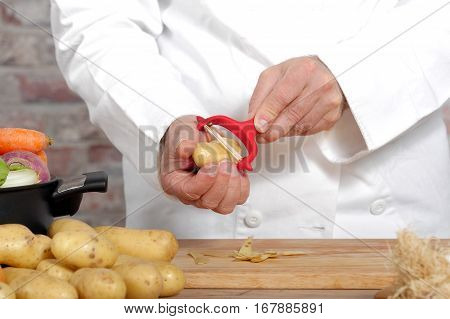 Hands of a man peeling potato with red peeler