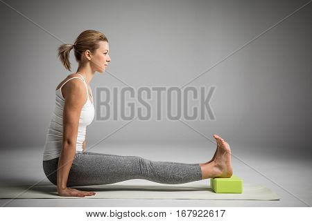Woman practicing yoga in Angusthasana handstand pose with yoga block