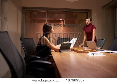 Businesswoman stands talking to colleague working late