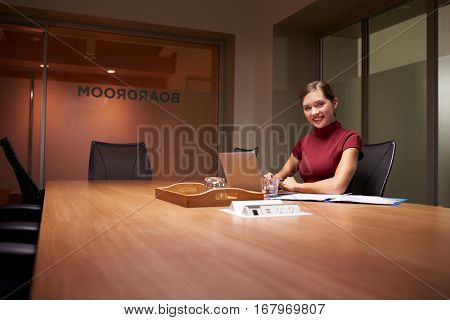 Young businesswoman working late in office smiles to camera