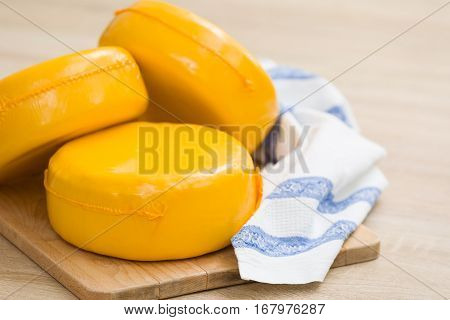 Three big organic cheese heads in yellow vacuum package laying on top of each other in the farm kitchen. Food concept