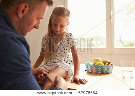 Father Putting Sticking Plaster On Daughter's Knee