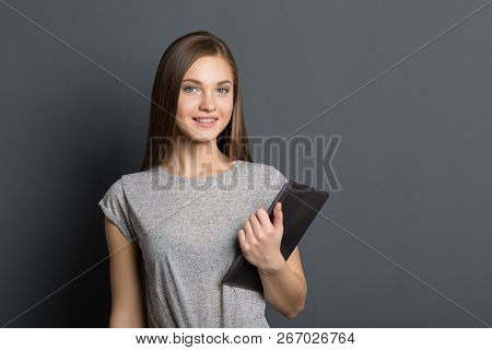 Beautiful Young Girl On A Gray Background Smiling. A Smiling Beautiful Young Girl In The Studio On A