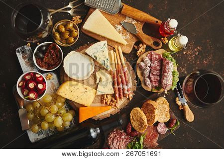 Huge assortment of various tasety spanish, french or italian apertizers. Cheese, meat, olives, stuffed peppers, bread, sticks. Placed on rusty dark background. View from above.