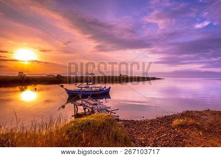 Fishing Boat In River Inlet Bay Under Orange Sunrise On Lesbos Island, Greece