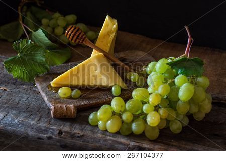 Slate Board With Various Cheese And A Glass Of Red Rose Wine. Gouda, Masdaam, Cheddar And Grapes On 
