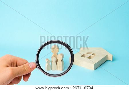 Magnifying Glass Is Looking At Thefamily Stands Near The Ruined Fallen House. Loss Of Housing, Home 