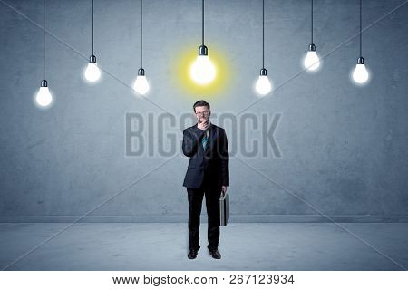 Handsome businessman in an empty space with bulbs above and uninspired face