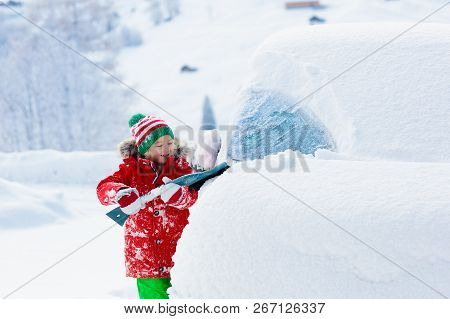 Child Brushing Off Car. Kid With Winter Snow Brush