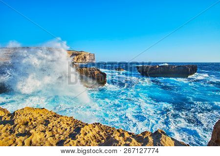 The Stormy Waves With White Splashes Cover The Rocky Coast Of San Lawrenz, Neighboring With Azure Wi
