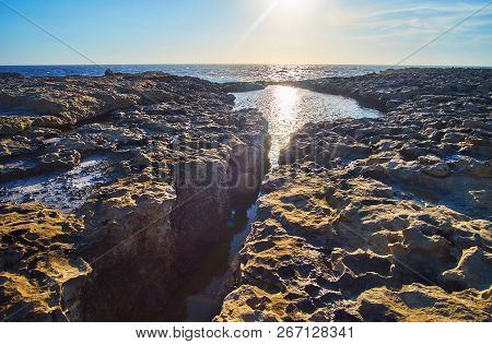 Indented Rocky Coast Of San Lawrenz Is Rich In Tiny Calm And Quiet Backwaters, Reflecting Sun And Sk